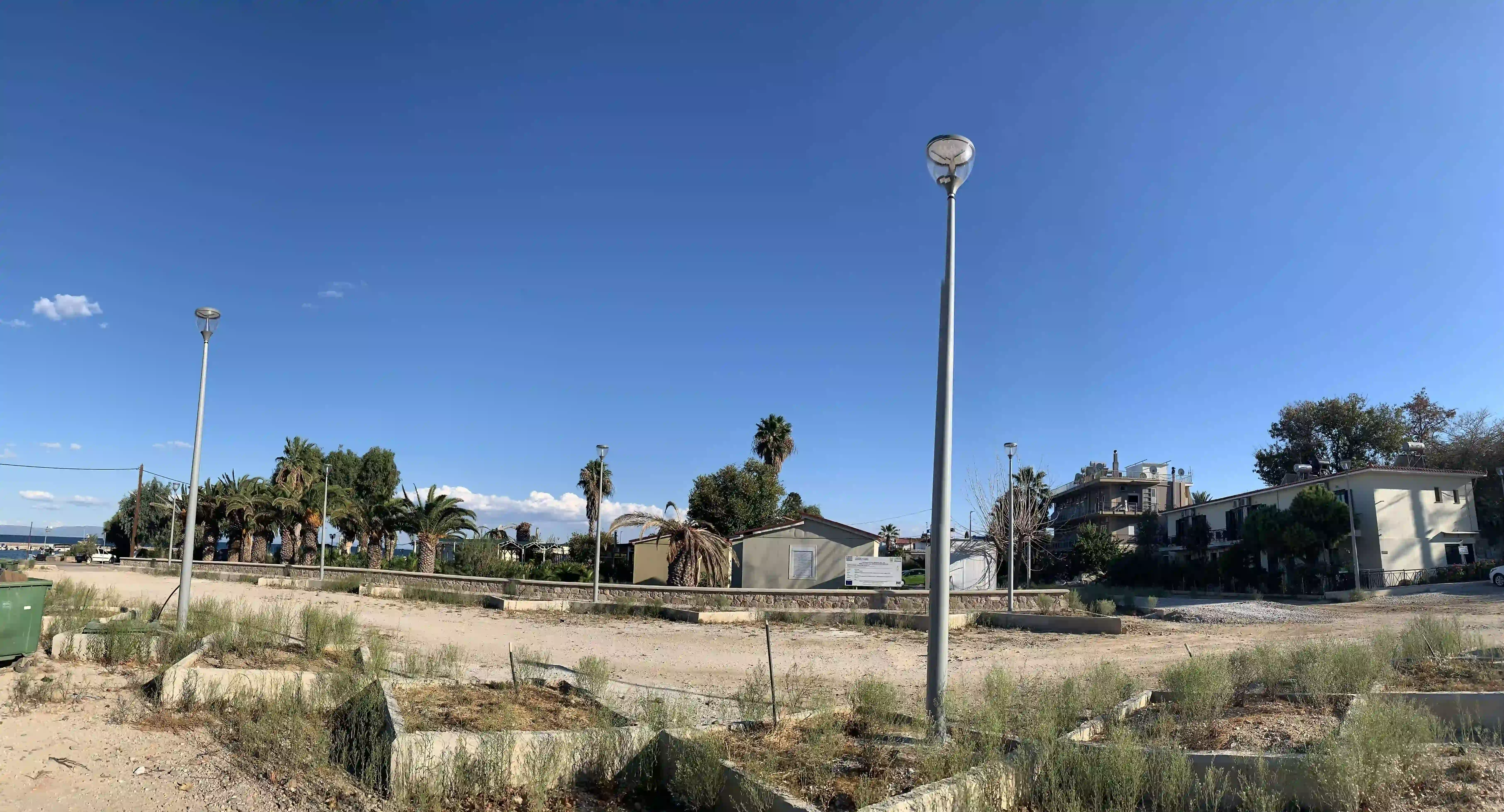 Απεικόνιση του μισού χώρου πάρκινγκ φωτογραφισμένο απο το κέντρο της σειράς των τεσσάρων ιστών και φαίνεται και η απέναντι σειρά των άλλων τεσσάρων ιστών μαζί με τα παρτέρια στη βάση τους.